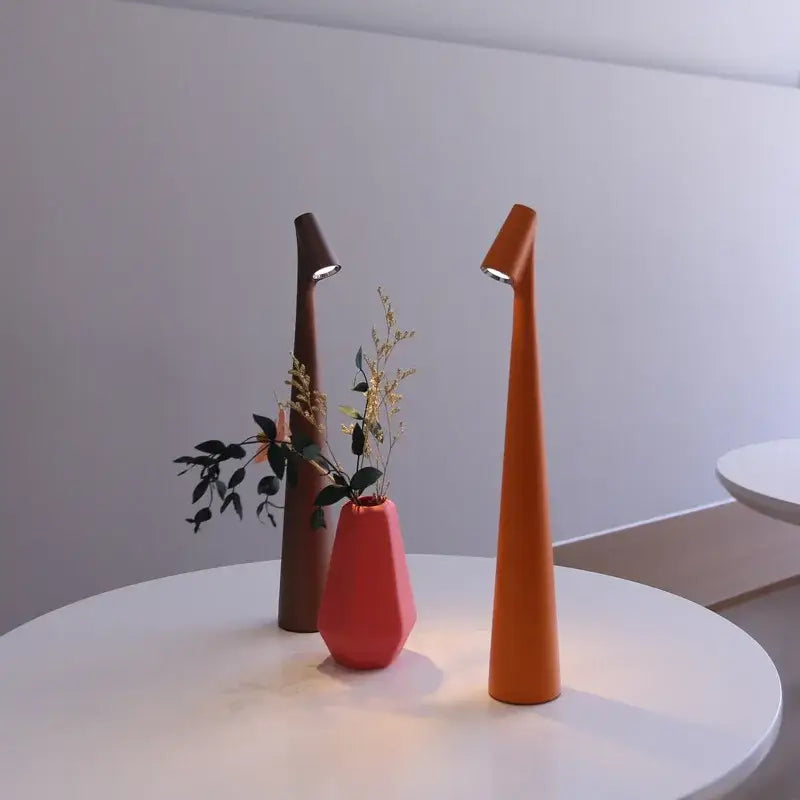 Two sleek led rechargeable desk lamps in warm orange and dark brown with tapered bodies and top touch dimming