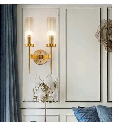 Gold-toned metal decorbites led sconce light with two vertical ribbed glass shades for bedroom and home use