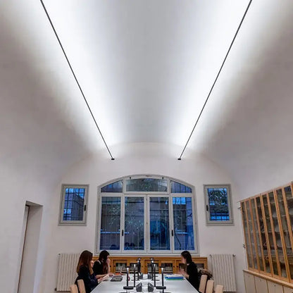 A modern conference room illuminated by decorbites led skyline linear wall light with minimalist design and large arched windows