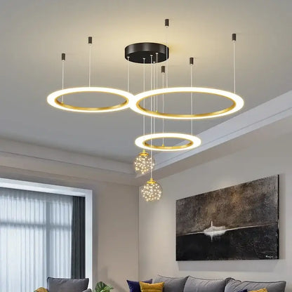 Modern gold-toned circular decorbites led star chandelier with black mounting plate and crystal globe pendants for living rooms