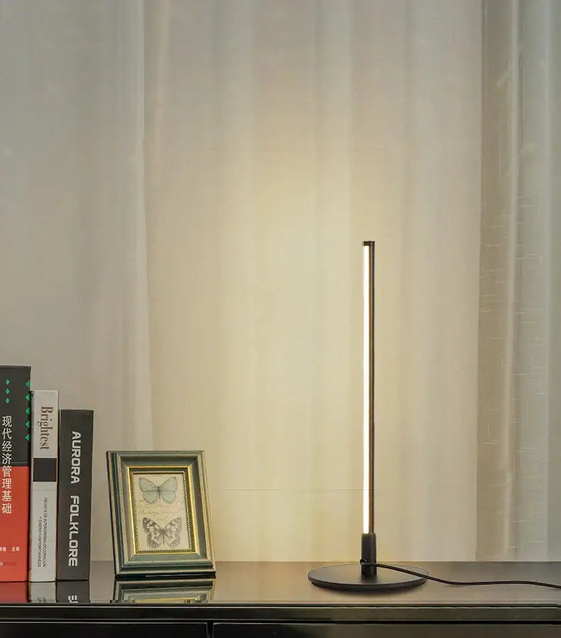 Minimalist black decorbites led table lamp with sleek slender vertical design and circular base for study and office lighting
