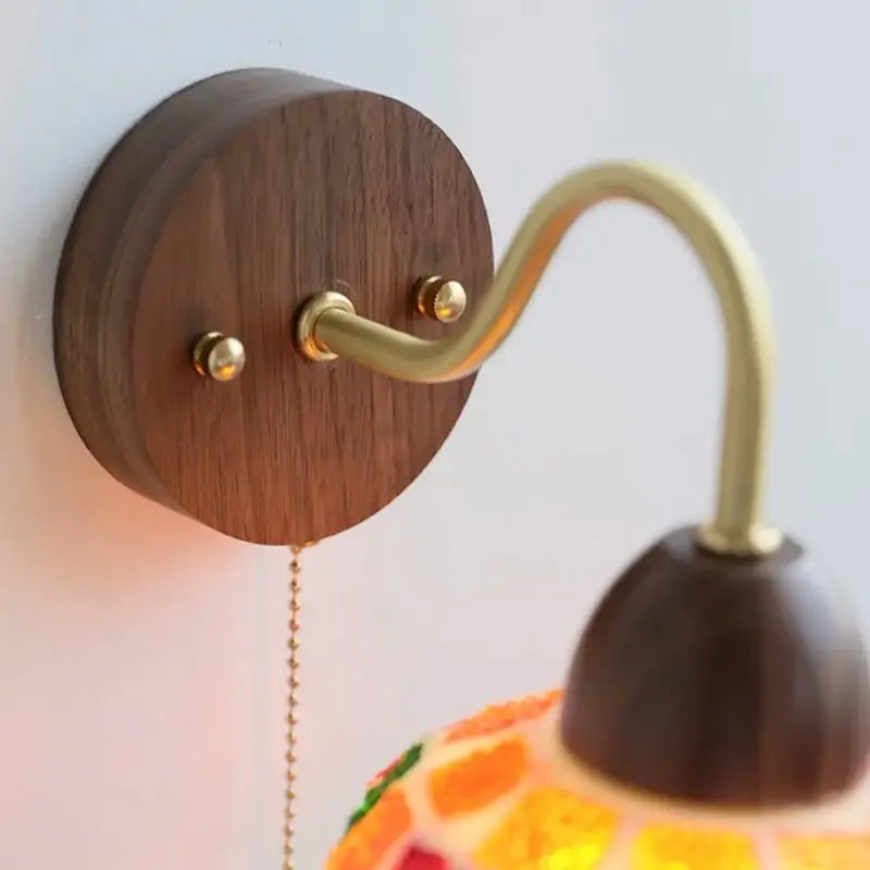 A decorbites led tiffany style wall light with a warm brass arm and orange yellow stained glass lampshade