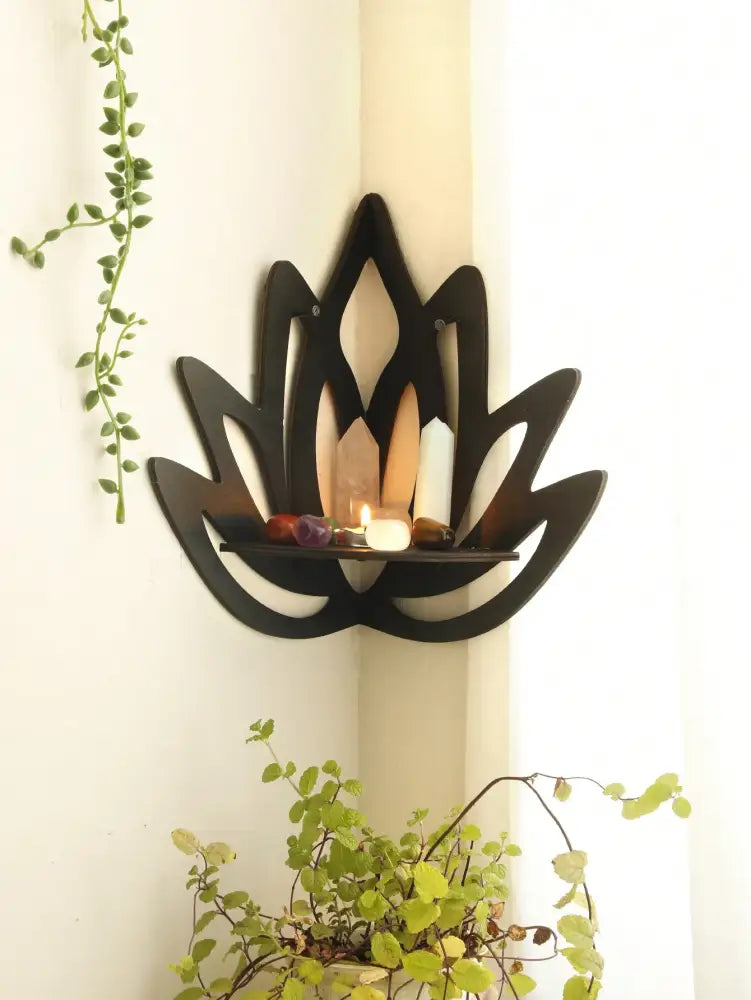 Black wooden lotus floating wall shelf with central platform holding candles and stones by DecorBites™