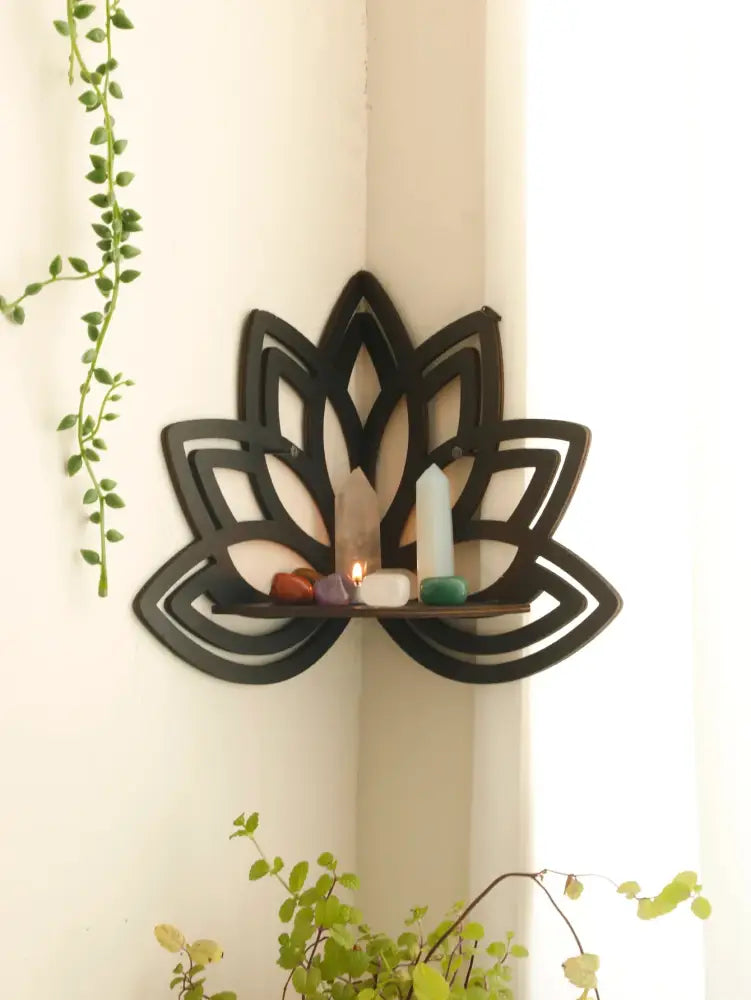 Black metal lotus floating wall shelf with central wooden slat displaying crystals and candles for home decor