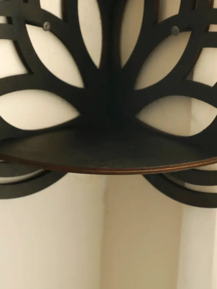 Black metal lotus floating wall shelf with leaf cutout design and dark wooden base for stylish home decor