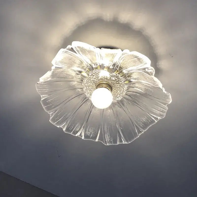 Clear glass ceiling light fixture with a petal-like design and central bulb.