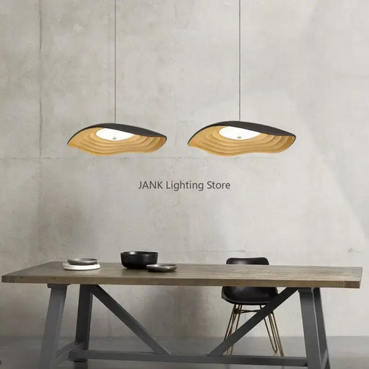 Two modern decorbites lotus leaf chandelier pendant lights with layered wave design in natural wood and black finish hanging above table