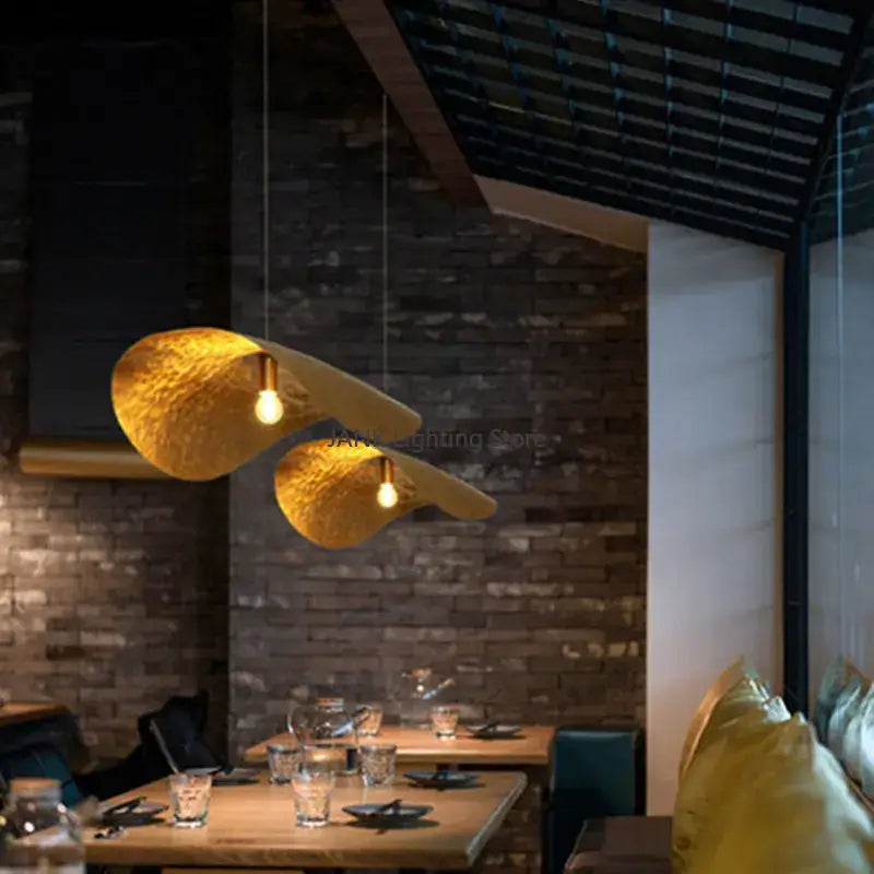 Two golden decorbites lotus leaf pendant lamps with hammered metal finish for elegant living room decor