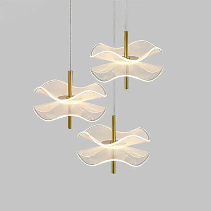 Three modern DecorBites™ lotus leaf pendant lights with translucent wave glass shades and gold metal stems for bedroom use