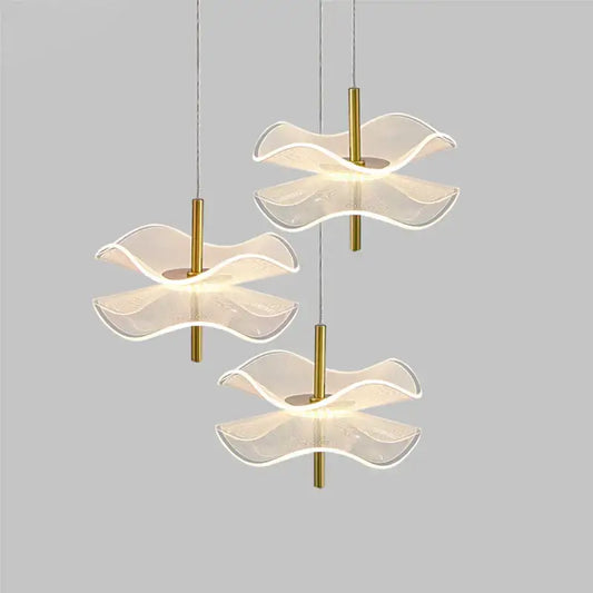 Three modern DecorBites™ lotus leaf pendant lights with translucent wave glass shades and gold metal stems for bedroom use