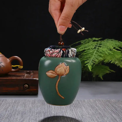 DecorBites™ lotus pattern ceramic tea pot storage jar in green with hand-painted lotus and fabric lid tied with brown cord