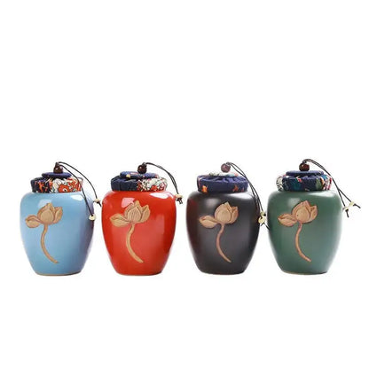 Four ceramic decorbites™ lotus pattern tea pot storage jars in blue red black and green with gold lotus decals and fabric lids