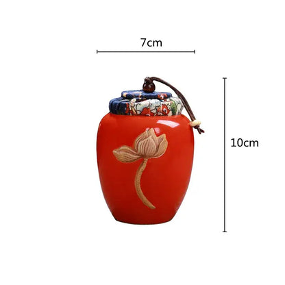 Vibrant red ceramic lotus pattern tea pot storage jar with hand-painted design and fabric lid secured by brown cord