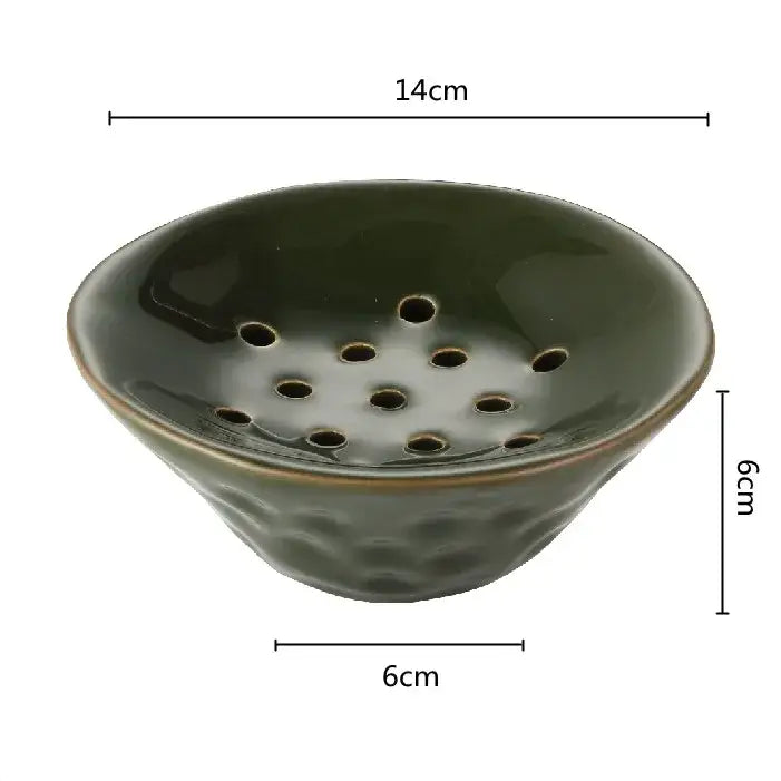 A dark green lotus root clay bowl with a textured hammered base and circular holes for home decor use
