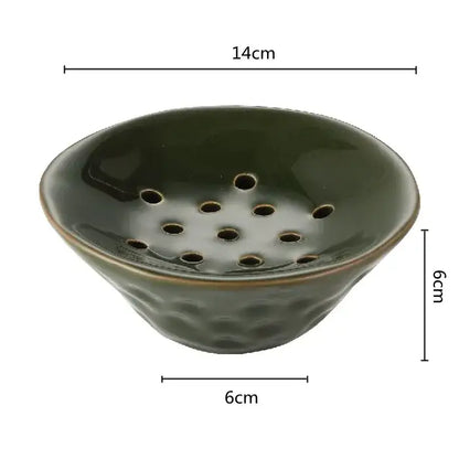 A dark green lotus root clay bowl with a textured hammered base and circular holes for home decor use