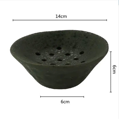 Dark green lotus root clay root clay bowl with textured speckled surface and circular holes for home decor use