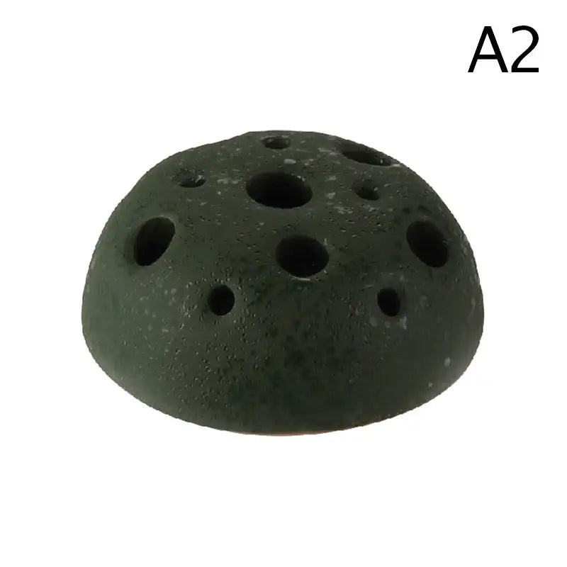 Dark green textured ceramic vase with circular holes inspired by lotus seedpod from decorbites stone sand set