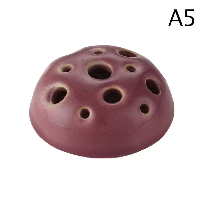A maroon ceramic vase featuring a lotus seedpod design with multiple circular holes by DecorBites stone sand