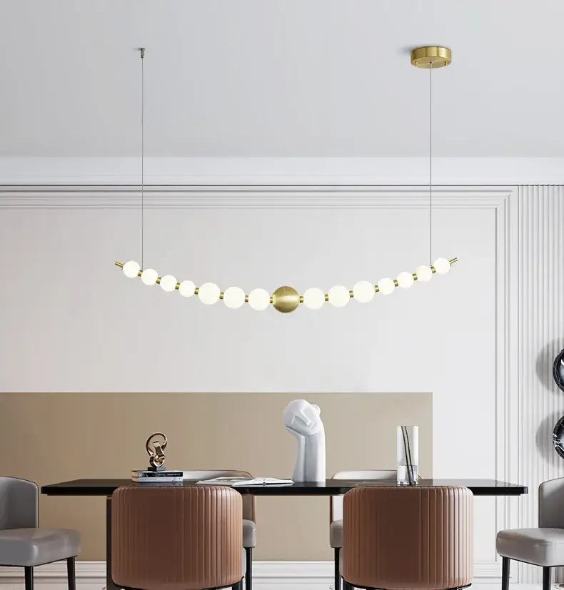 Gold-toned pendant light with spherical glass bulbs in an elegant curve for dining by decorbites love gold chrome chandelier