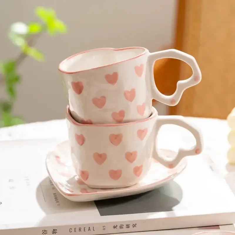 A pair of white ceramic DecorBites love heart hand painted coffee mugs with pink hearts and heart-shaped handles