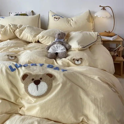 Cream-colored DecorBites™ embroidered bedding set featuring plush teddy bear appliqué and blue lucky day text