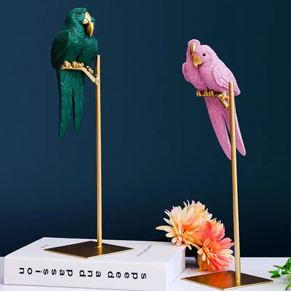 Two decorative decorbites lucky parrot resin ornaments in emerald green and soft pink on gold stands for modern home decor