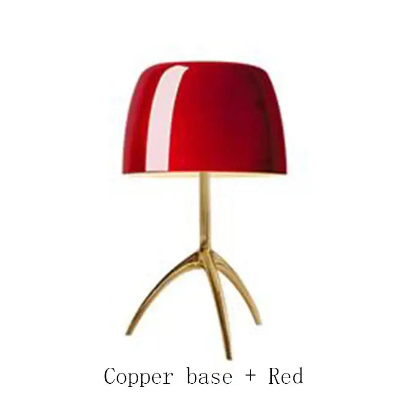 A sleek red decorbites lumiere piccola chrome table lamp with a glossy finish and copper tripod base for bedside use