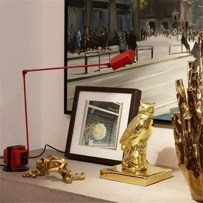 Gold owl figurine with polished metallic finish and detailed feathering on square base beside decorbites lumina long arm floor lamp