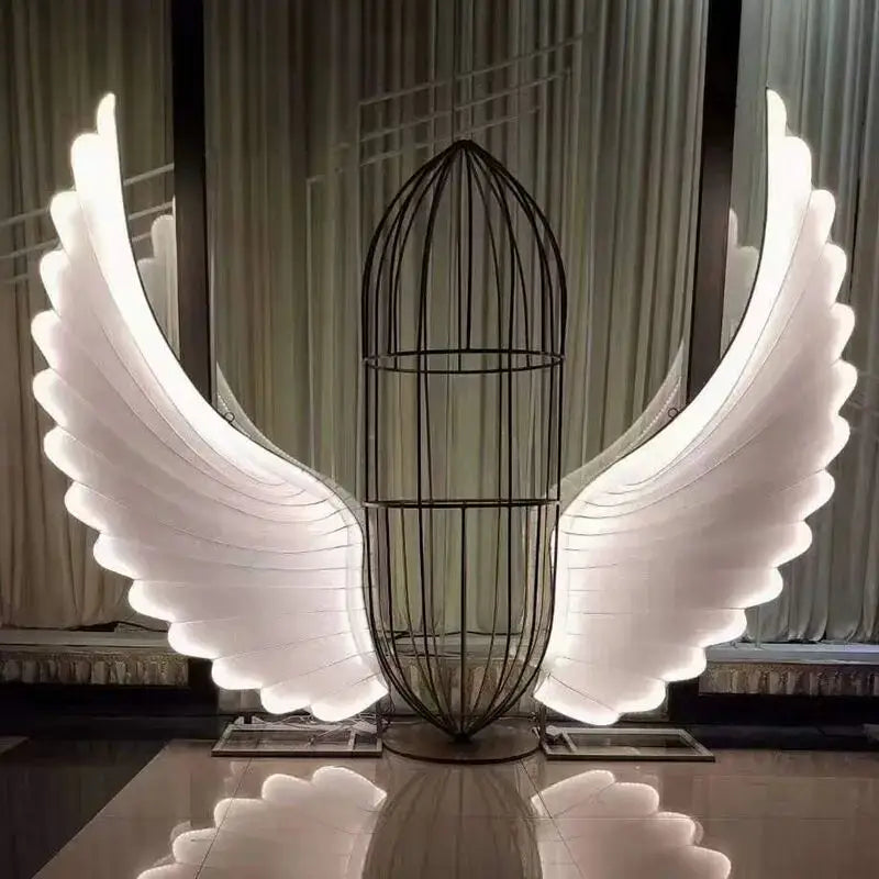 A glowing white led angel wings lamp with a black wire cage body by decorbites luminescent angel wings for stage decor