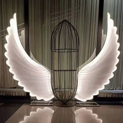 A glowing white led angel wings lamp with a black wire cage body by decorbites luminescent angel wings for stage decor