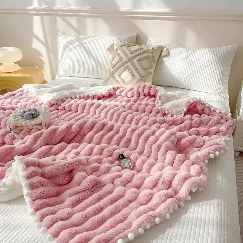Pink chunky knit throw blanket with white pom-pom trim and faux rabbit fur texture for cozy bed warmth by DecorBites™