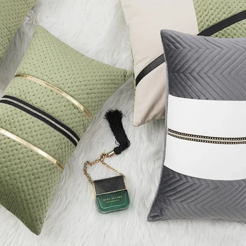 A small green marc jacobs perfume bottle charm with black tassel and gold chain shown with decorbites luxe gray white cushion cover for modern home decor