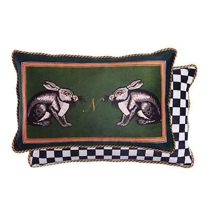 Dark green velvet decorative pillow cover with embroidered rabbits, gold monogram, orange border, and braided trim
