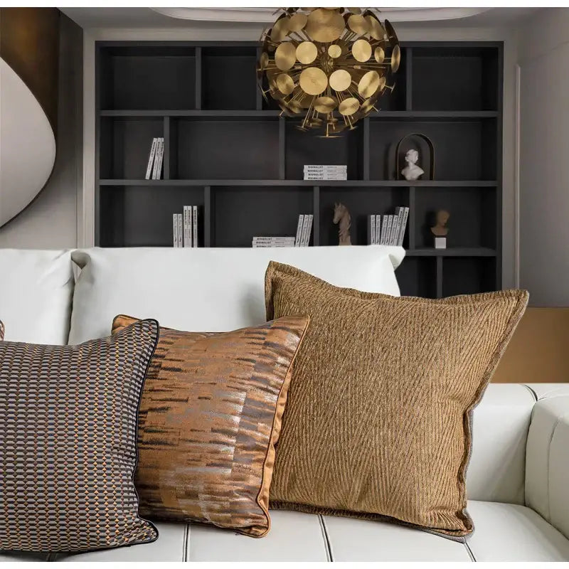 Three decorbites luxe jacquard cushion covers in brown gold coffee colors with textured fabric on a white sofa