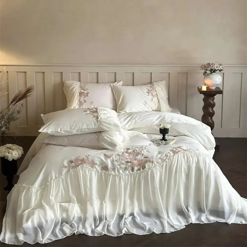 White satin bedding set with pink floral embroidery and ruffled edges from DecorBites luxe lace ruffles collection