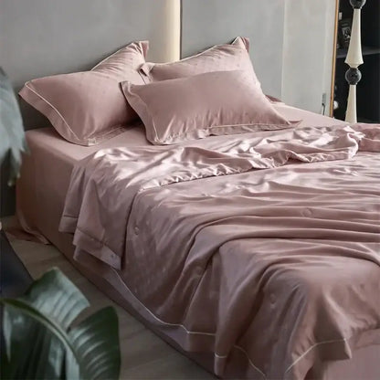 A soft blush pink decorbites luxe lyocell summer blanket with mulberry silk fill and delicate white piping edges