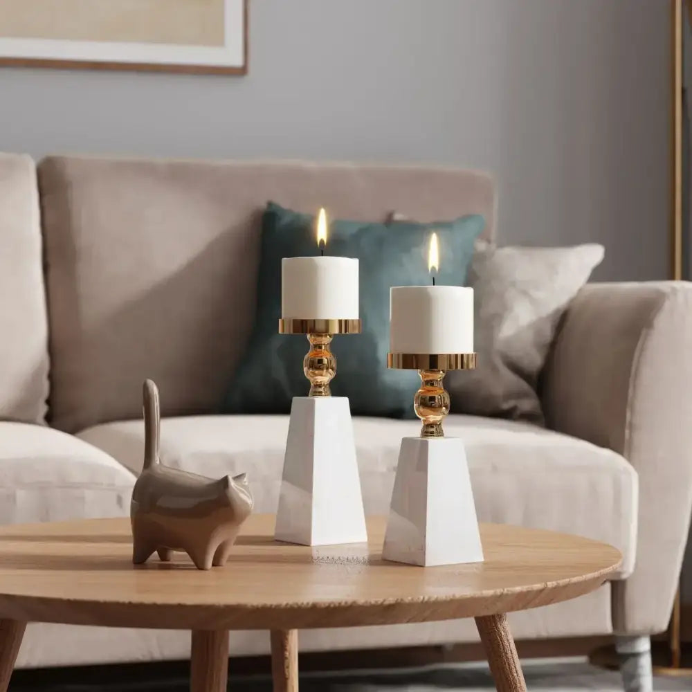 Two elegant white marble candle holders with gold-toned metallic bases holding lit white pillar candles showcasing DecorBites™ luxe marble candle holder modern minimalist style