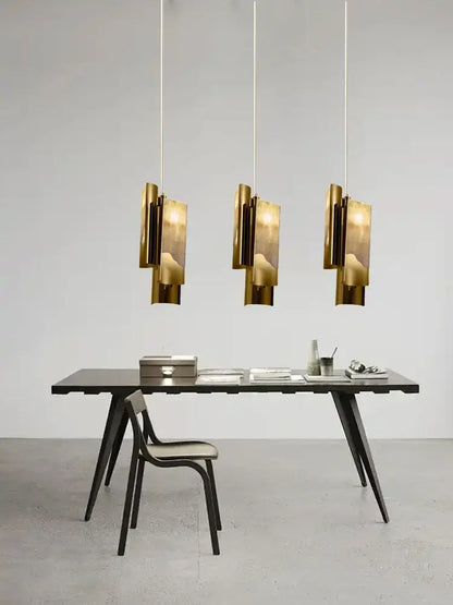 Three modern bronze decorbites luxe marble pendant lights with geometric design hang above a minimalist desk