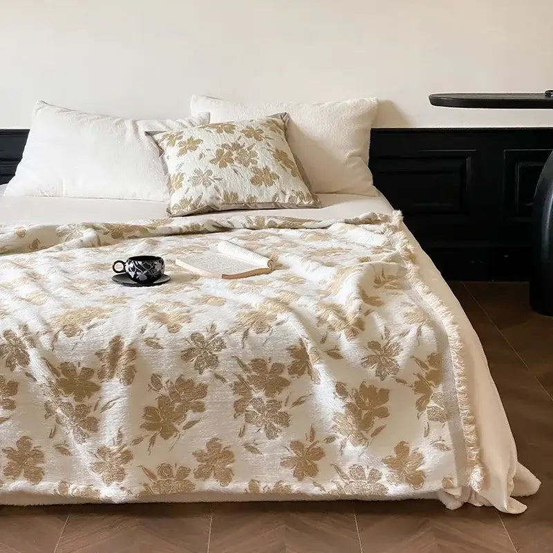 Cream-colored decorbites luxe mink fur jacquard throw with gold floral pattern and soft fringed edges for cozy warmth