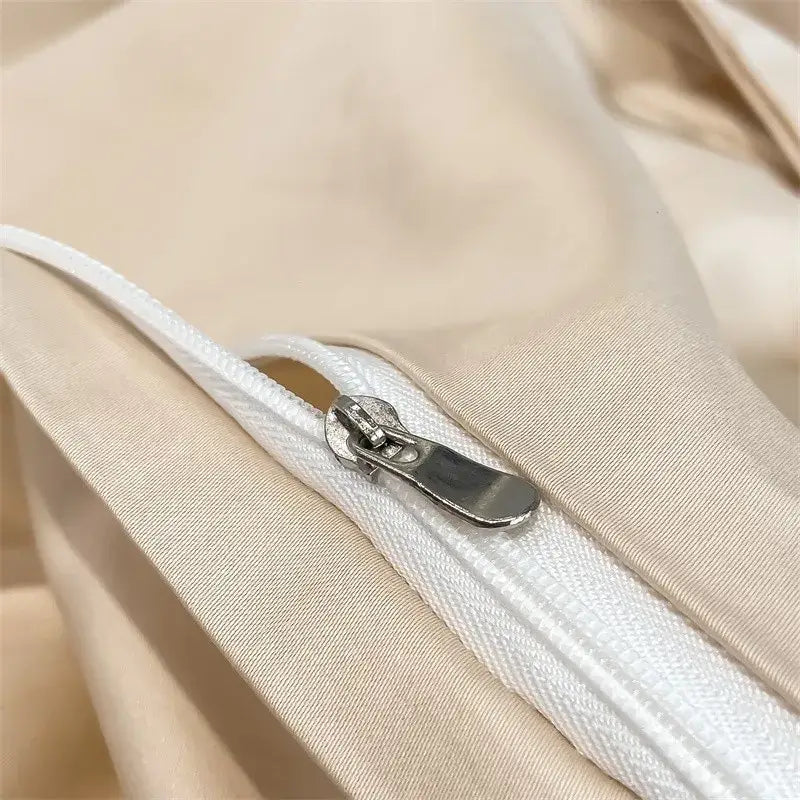 A sleek silver zipper with a metallic pull tab on a beige 1000tc egyptian cotton duvet cover from DecorBites™
