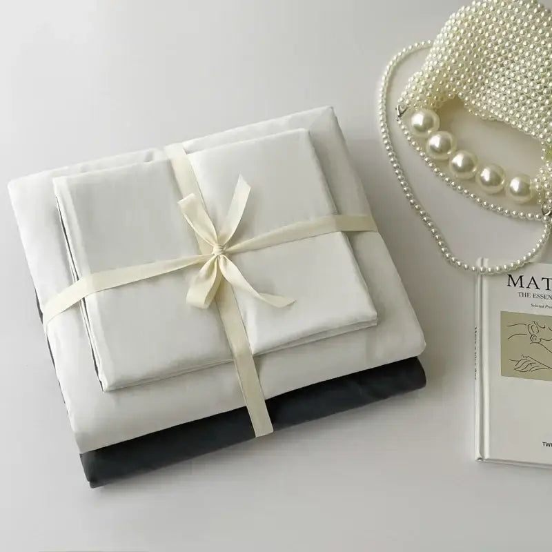 Decorbites luxurious white cotton bedding set neatly folded and tied with a cream ribbon for single and couple beds