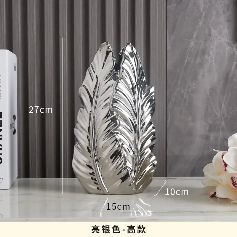 Shiny silver leaf-shaped ceramic vase complementing luxurious gold ceramic vases for elegant home decor
