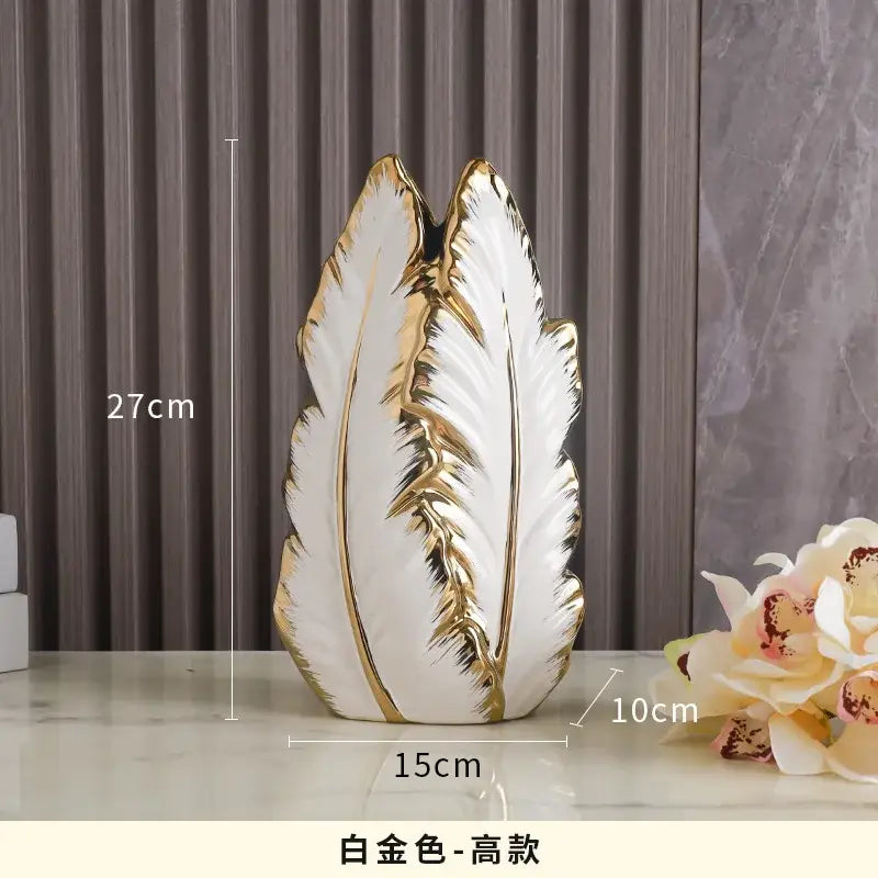 White and gold ceramic vase shaped like a stylized leaf with intricate golden veins for luxurious gold ceramic home decor