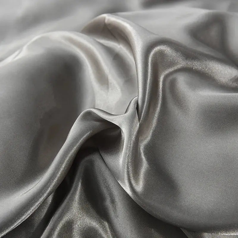 Decorbites luxurious silk bedding set featuring silver-gray satin bed sheet with smooth glossy finish and flowing folds