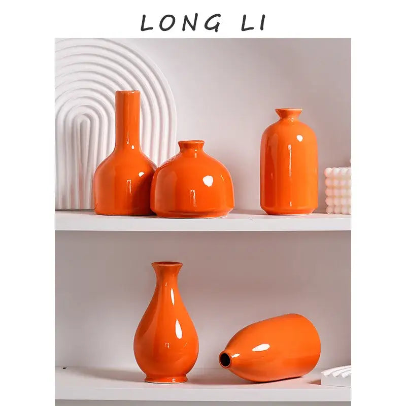 Set of five luxury modern ceramic orange vases with varied shapes and glossy finishes displayed on white shelves