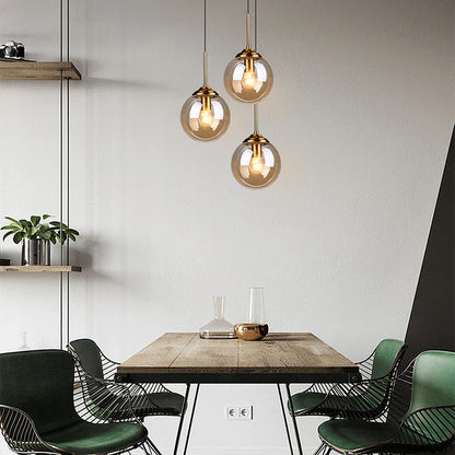 DecorBites luxury nordic led chandelier with three glass shades and brass fixtures above a wooden dining room table