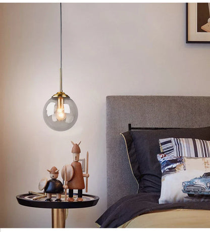 A luxury nordic led chandelier with clear glass globe and brass accents hanging above a dining room table