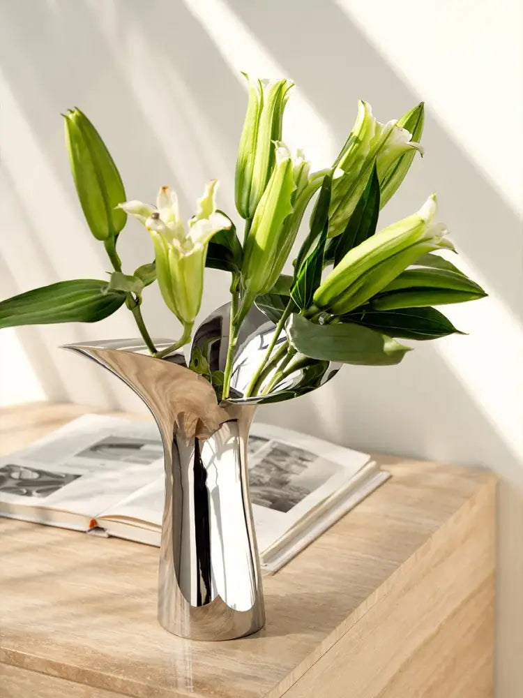 A sleek silver-toned luxury stainless steel vase by DecorBites holding fresh green lily buds and blooms for home decor