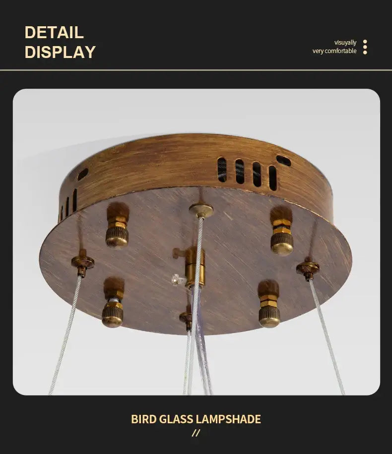 Bronze-finished ceiling pendant bird chandelier with circular wooden base and six hanging glass bird lampshades from DecorBites™