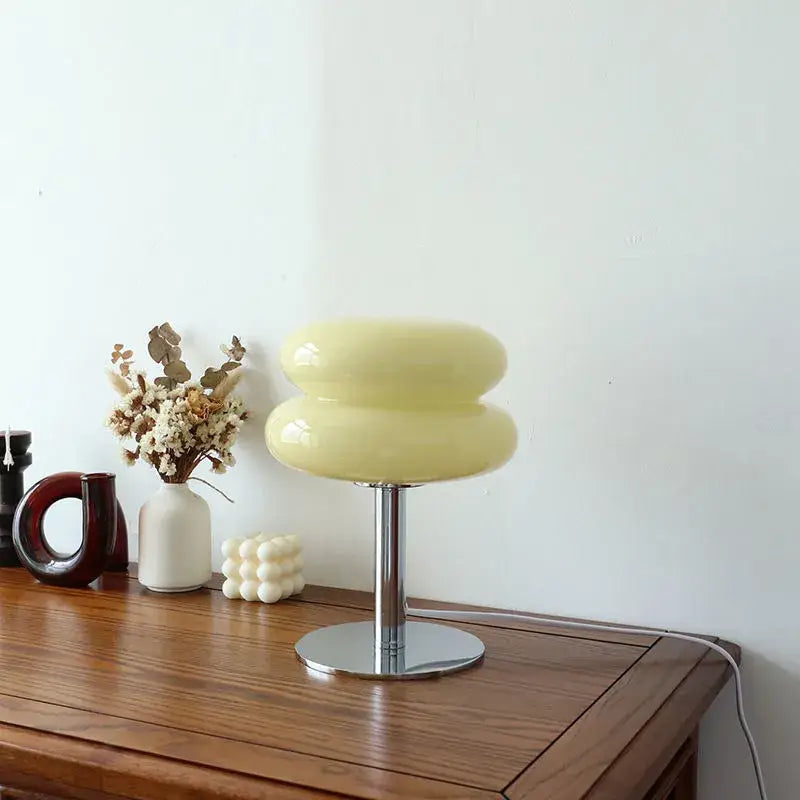 A sleek pale yellow glass DecorBites macaron lamp with stacked oval design and polished chrome base by italian designer
